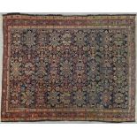 A Heriz style rug with all over repeating floral motifs on a deep blue ground within stylised