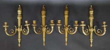 A set of four gilt bronze twin branch wall sconces with scrolling foliate arms on reeded columns