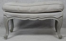 A painted Louis XV style footstool in double piped calico upholstery on carved scrolling cabriole