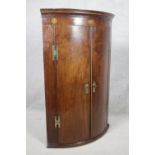 A Georgian figured mahogany bowfronted corner cupboard with satinwood and olivewood conch and floral