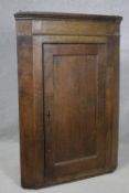 A Georgian country oak corner cupboard with panel door enclosing shaped shelves. H.117 W.81 D.41cm