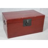 A Chinese red lacquered hardwood travelling trunk with twin metal carrying handles and lock. H.37