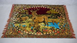 A vintage red velvet tapestry with stags and deers in a woodland clearing by a lake. H.170 W.120cm