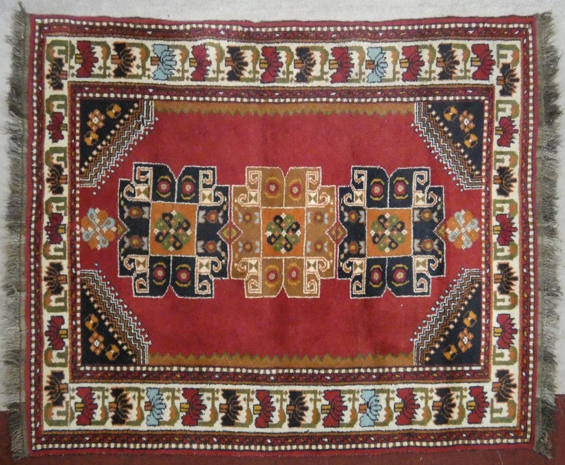 A Turkish Kars rug with repeating medallions on madder ground within spandrels and stylised lotus