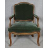 A French style carved walnut framed open armchair in velour upholstery on cabriole supports. H.93