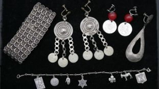 A collection of silver jewellery. Including an Israeli silver charm bracelet, silver coin earrings a