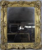 A 19th century carved giltwood and gesso wall mirror with scrolling Rococo frame and original plate.