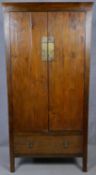 A Lombok teak hall cupboard with panel doors enclosing shelves above base drawer on block
