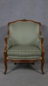 A French style carved walnut framed armchair in striped upholstery on cabriole supports. H.97cm