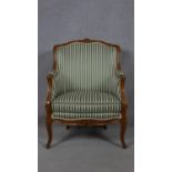 A French style carved walnut framed armchair in striped upholstery on cabriole supports. H.97cm