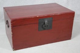 A Chinese red lacquered hardwood travelling trunk with twin metal carrying handles and lock. H.37