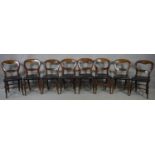 A set of eight Victorian carved mahogany balloon back chairs on swept turned stretchered supports.