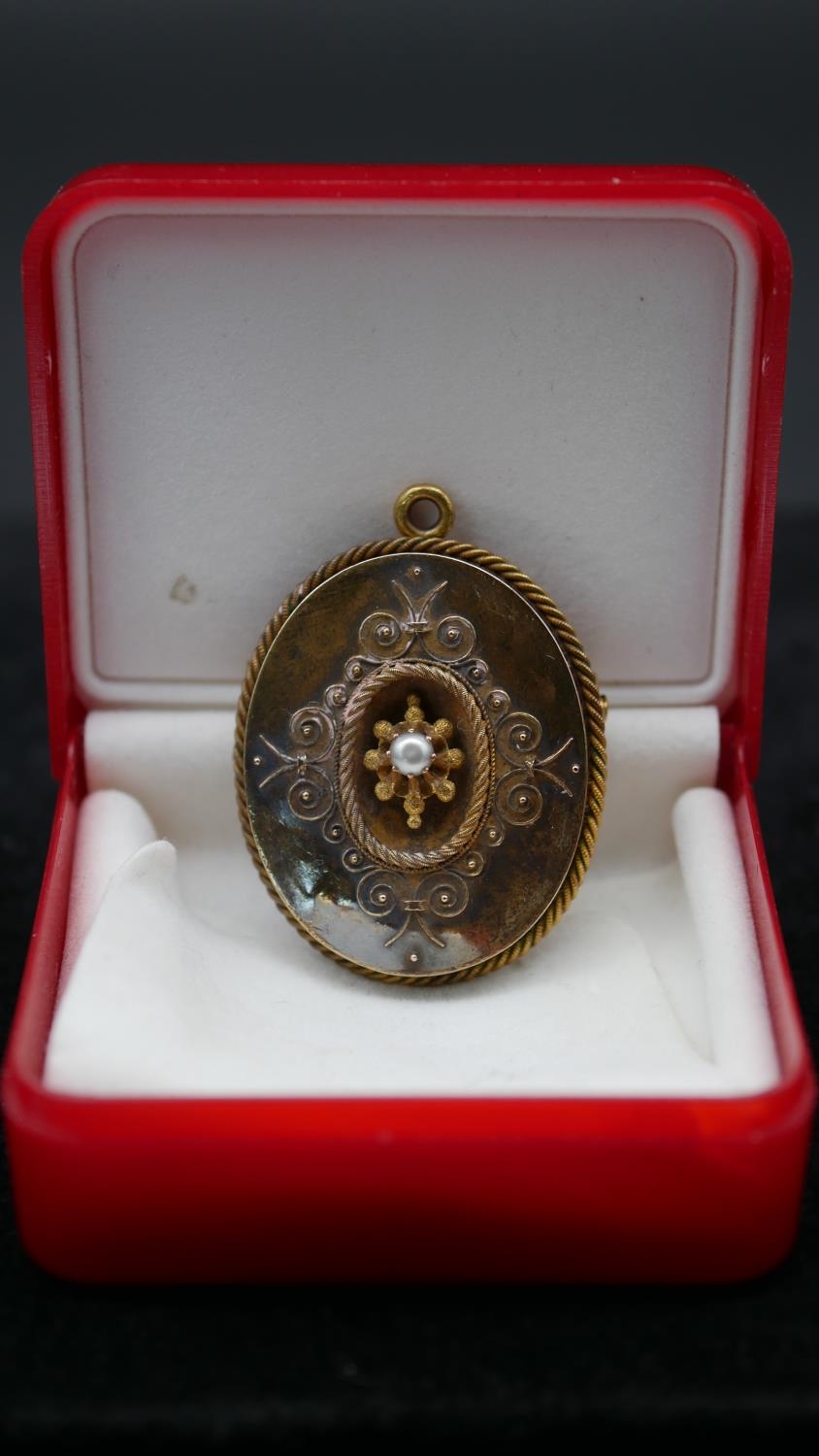 A Victorian yellow metal and pearl filigree detailed brooch/pendant. With secure hinged pin to the