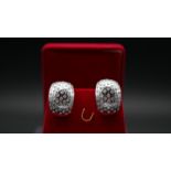 A red velvet boxed pair of half hoop white metal (tested 18 carat white gold) and diamond pierced