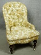 A Victorian beech framed nursing chair in deep buttoned floral upholstery on turned tapering