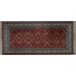 A Persian style rug with repeating petal motifs across a burgundy field contained within