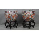 A pair of early 20th century glazed Chinese Imari ceramic planters/fish bowls on carved hardwood