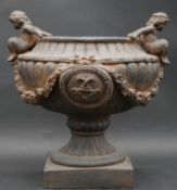 A moulded garden urn with twin cherub handles and reeded sides with swag decoration on plinth