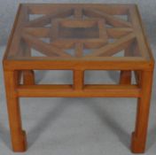 A Chinese influenced hardwood occasional table with inset plate glass top on shaped square section