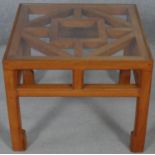 A Chinese influenced hardwood occasional table with inset plate glass top on shaped square section