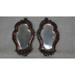 A pair of C.1900 pier mirrors with shaped bevelled plates in foliate carved mahogany frames. H.63.