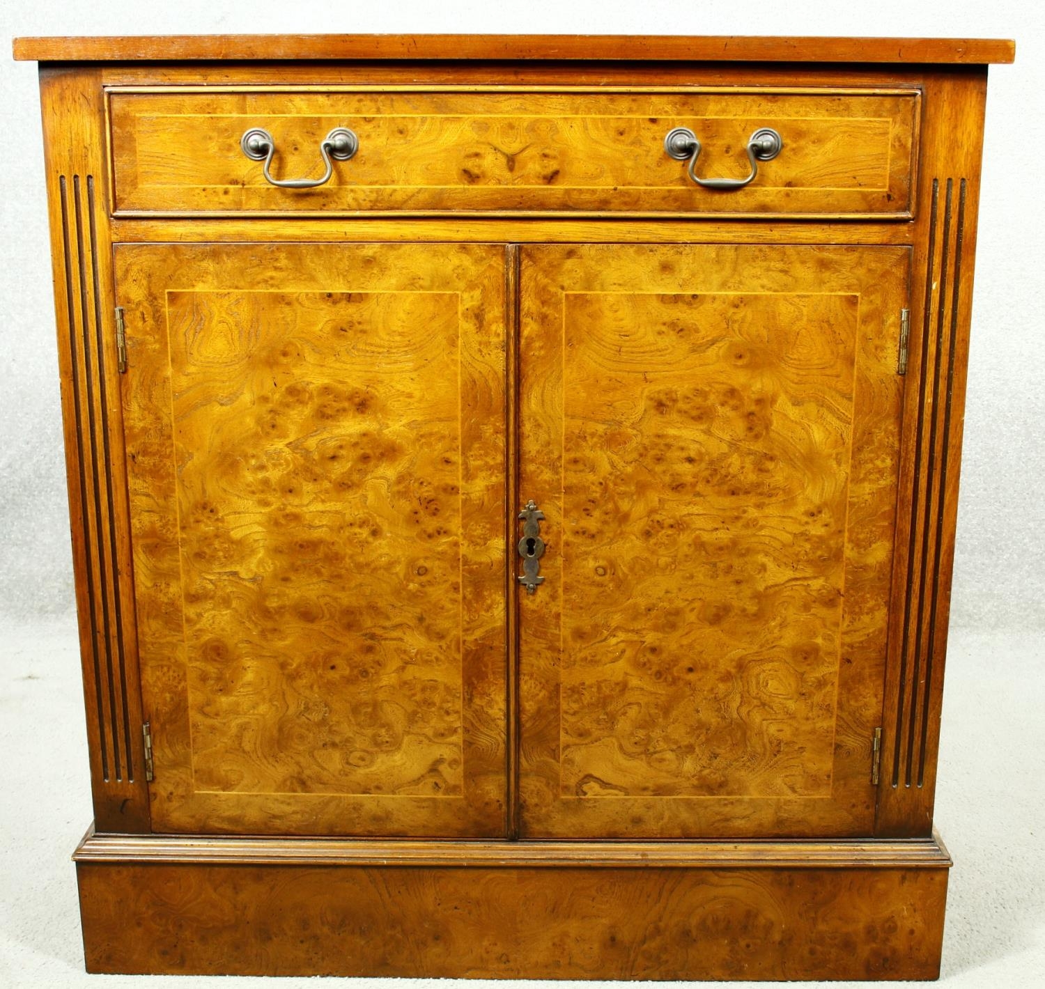 A Georgian style burr elm and satinwood strung side cabinet with frieze drawer above panel doors