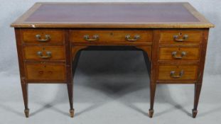 An Edwardian mahogany and crossbanded kneehole desk with inset leather top raised on square tapering