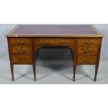 An Edwardian mahogany and crossbanded kneehole desk with inset leather top raised on square tapering