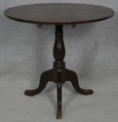 A Georgian oak tilt top occasional table on baluster turned pedestal and tripod cabriole supports.