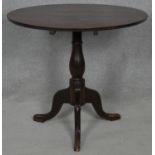 A Georgian oak tilt top occasional table on baluster turned pedestal and tripod cabriole supports.