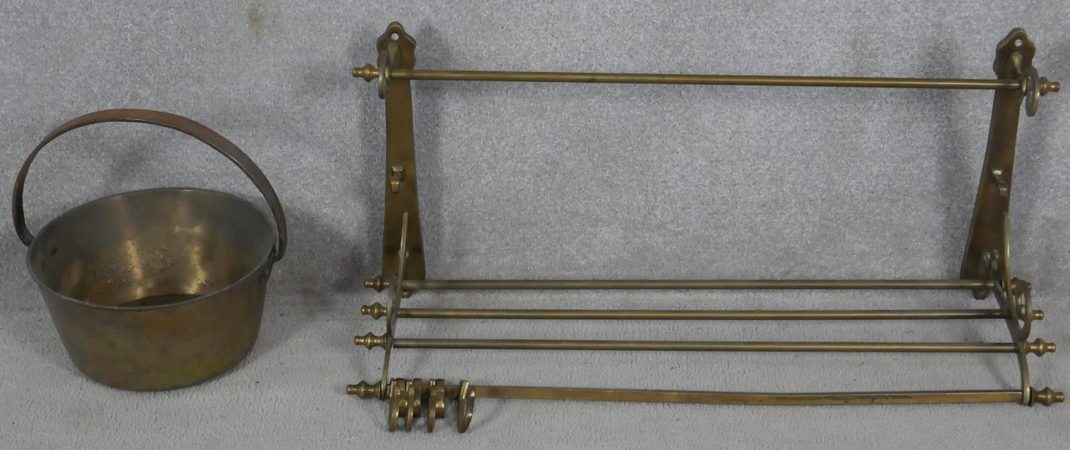 A 19th century brass wall mounted kitchen utilities rack and a heavy brass Victorian swing handled