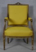 A 19th century Louis XVI style giltwood fauteuil with carved back rail and arms raised on tapering