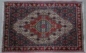 A Persian rug with triple lozenge medallions on stylised floral ground and borders. L.114 W.73cm