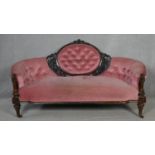 A Victorian carved walnut framed sofa in deep buttoned velour upholstery on fluted tapering