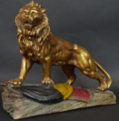 A gold and polychrome glazed ceramic sculpture of a lion roaring and standing on the Belgian flag on