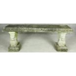A weathered reconstituted stone garden bench on twin supports. H.46 W.128 D.38cm