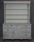 A late 19th century distressed painted pine kitchen dresser with upper open plate rack above base