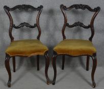 A pair of late 19th century mahogany dining chairs with carved and shaped back rails on cabriole