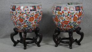 A pair of early 20th century glazed Chinese Imari ceramic planters/fish bowls on carved hardwood