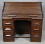 A late 19th century oak roll top desk with tambour shutter revealing fitted interior on twin