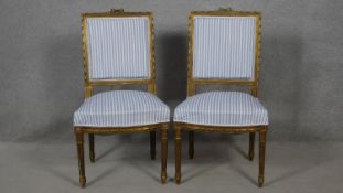 A pair of 19th century Louis XVI style carved giltwood dining chairs in striped upholstery on fluted