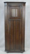 A mid century oak Jacobean style floor standing hall cupboard with carved linenfold panel door on