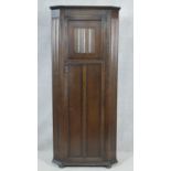 A mid century oak Jacobean style floor standing hall cupboard with carved linenfold panel door on