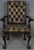 A mid Georgian style mahogany library armchair in deep buttoned and studded leather upholstery