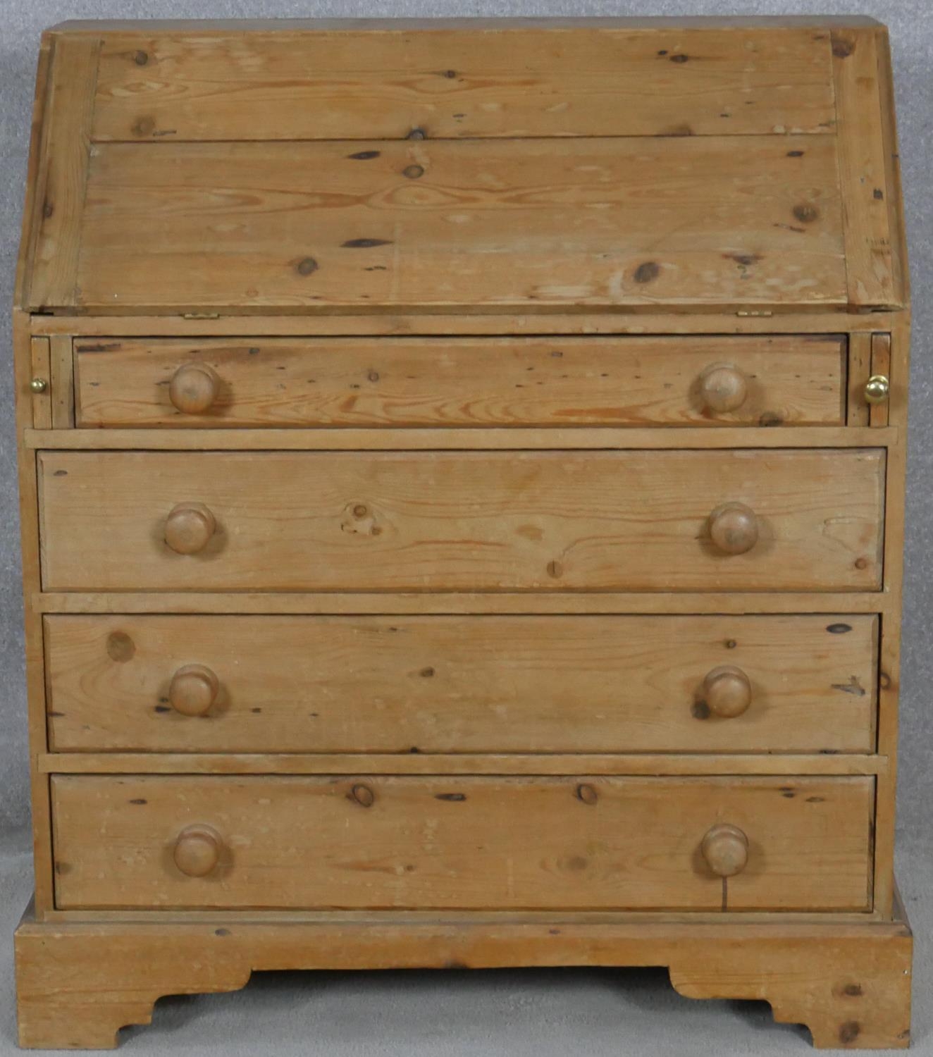 A 19th century pine bureau with fall front revealing a fitted interior above four long graduated