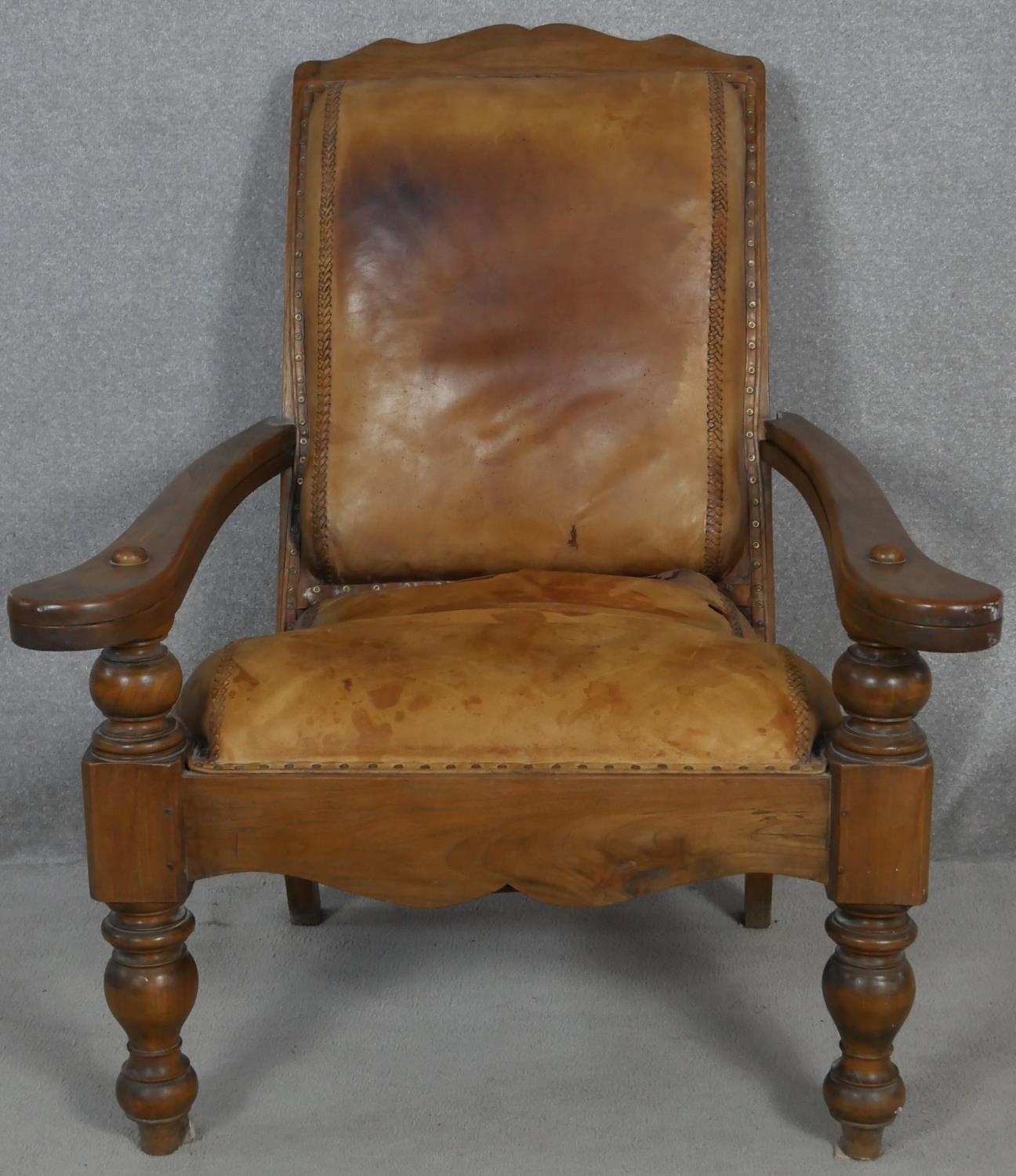 A 19th century teak planter's style armchair with folding leg rests in leather upholstery on