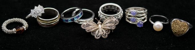 A collection of nine rings and a silver butterfly filigree brooch. Including two Swarovski and