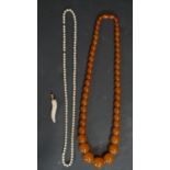 A graduated antique amber necklace, a string of glass pearls and a 9 carat rose gold wrapped antique