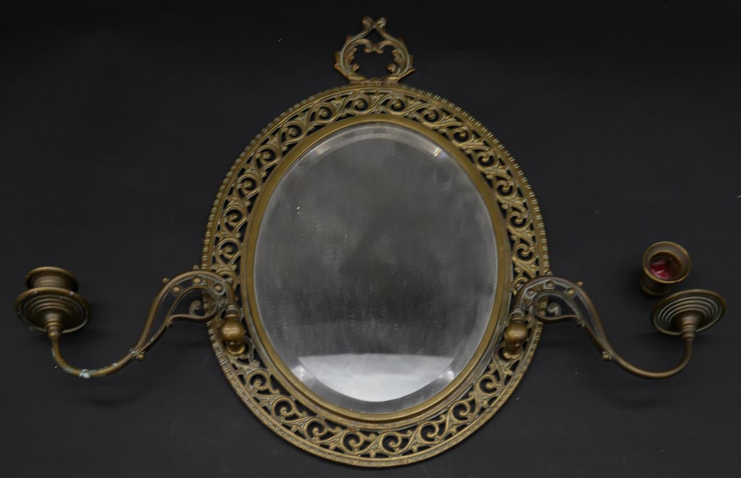 A late 19th century gilt metal twin branch girandole with bevelled plate in pierced floral frame.