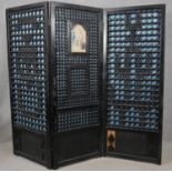 A Chinese style ebonised three panel room divider with central panel inset with glazed watercolour